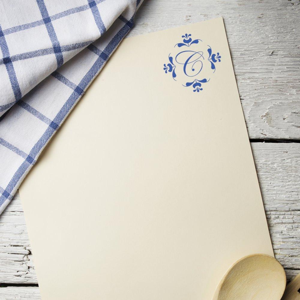 Custom monogram rubber stamp on cream invitation card with blue floral C, perfect for wedding stationery and branding.