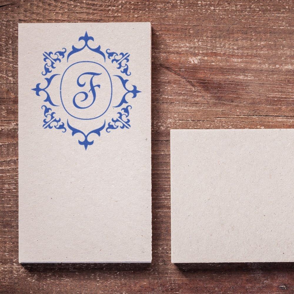 Custom rubber stamp with ornate monogram F on blank card, showcasing elegant personalized stationery design.
