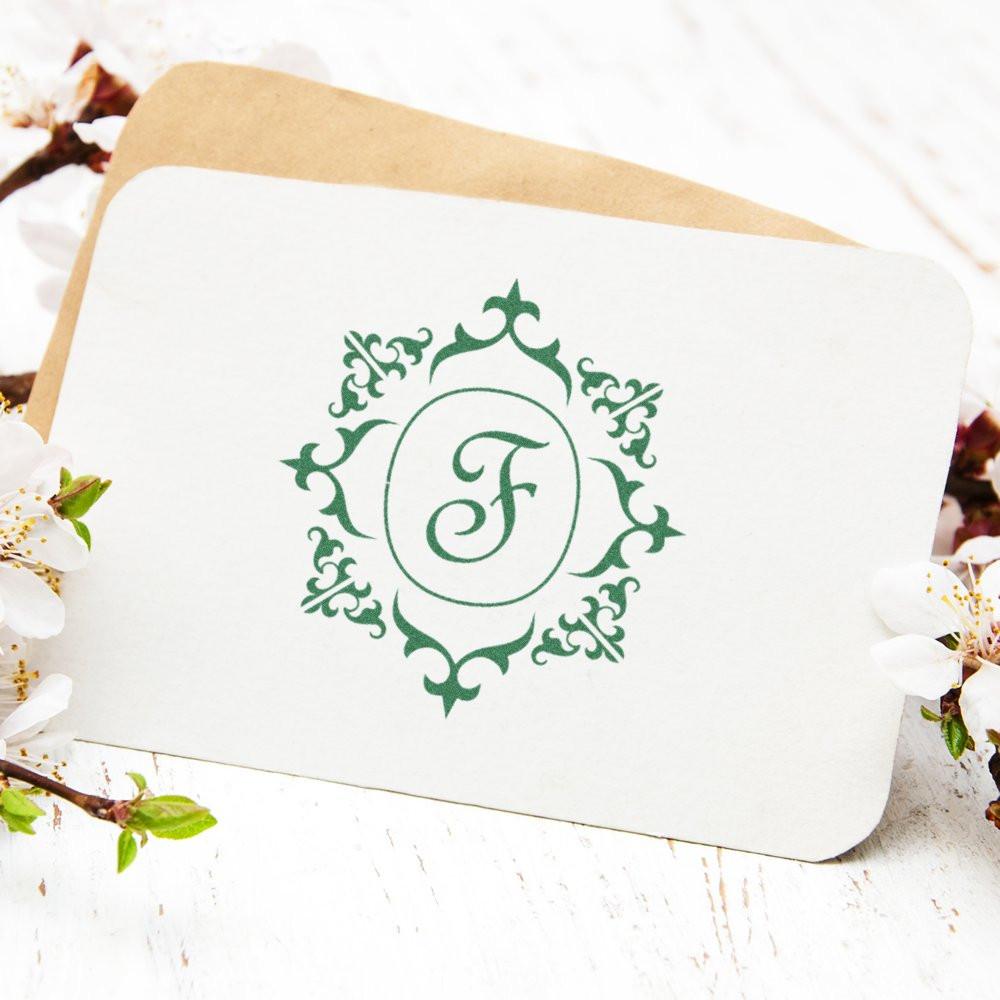 Personalized monogram F thank-you card with ornate green crest, wedding stationery on whitewashed wood with spring flowers, branding.