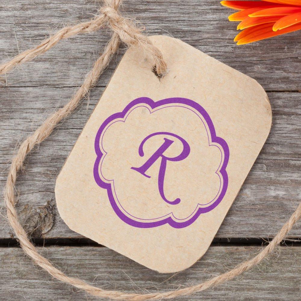 Purple monogram R custom rubber stamp on kraft gift tag, perfect for personalized branding and packaging.