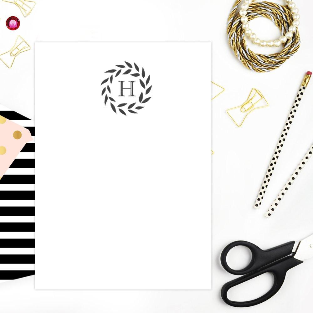 Custom monogram rubber stamp mockup with laurel wreath H on blank stationery, ideal for personalized branding and wedding favors.