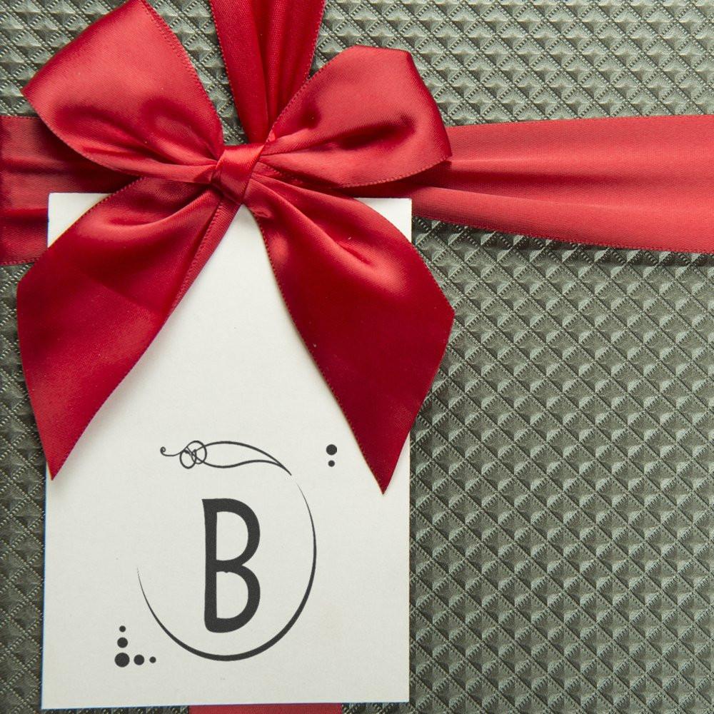 Personalized rubber stamp design with letter B on a gift tag, tied with a red ribbon for custom packaging.