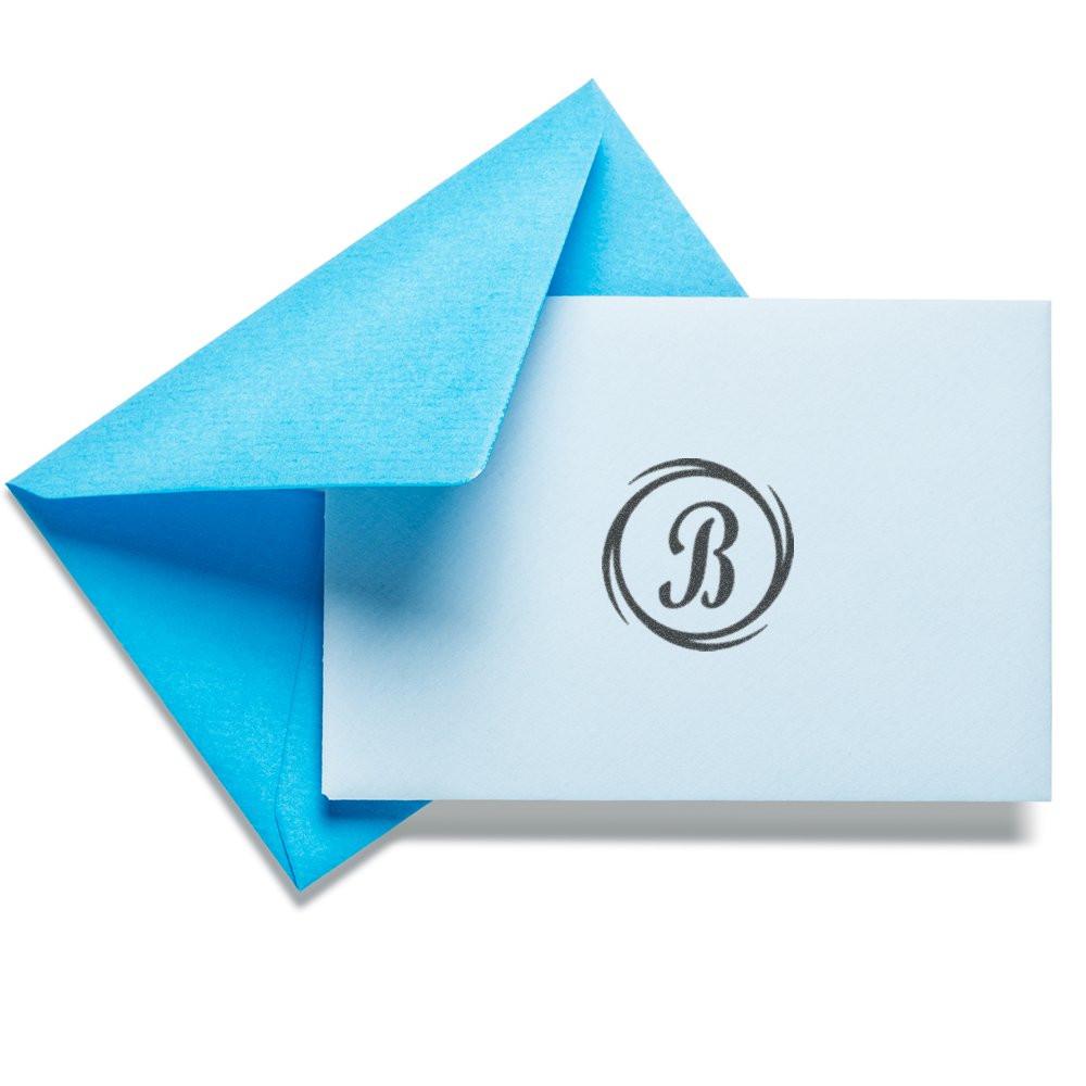 Custom monogram rubber stamp on envelope and card with blue lining, ideal for personalized stationery and business branding.