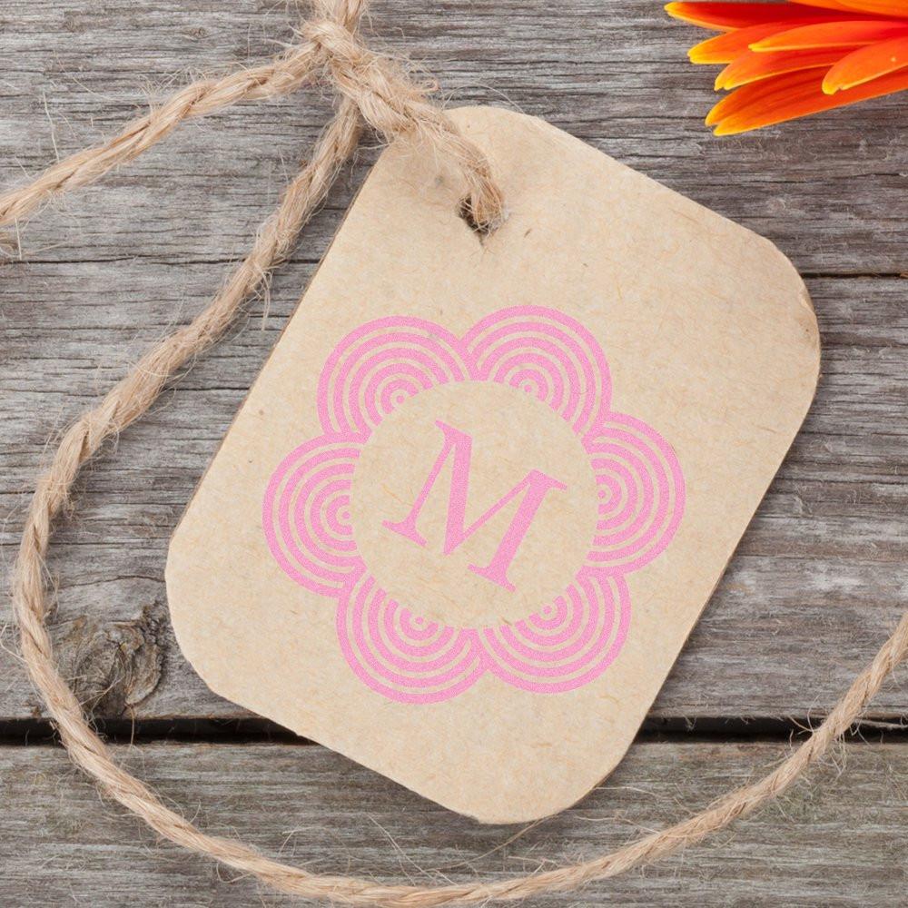 Custom floral monogram M rubber stamp on kraft gift tag, ideal for branding packaging and handmade products.
