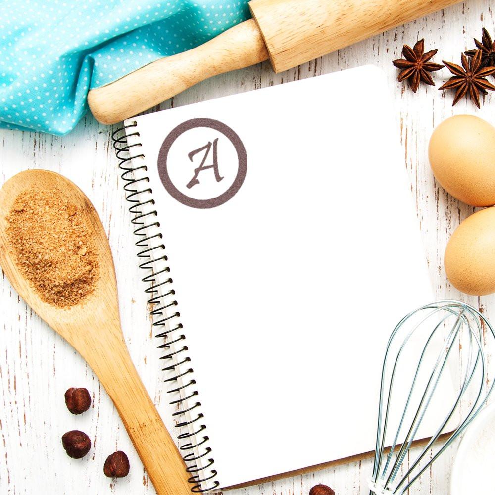Personalized monogram rubber stamp on a recipe notebook, perfect for custom kitchen labeling, baking journals, and handmade gifts.
