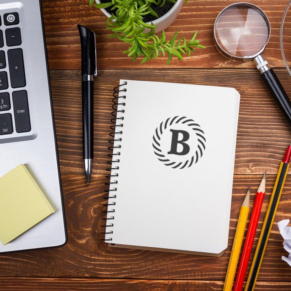 Custom rubber stamp monogram B on notebook for business branding and personalized stationery.