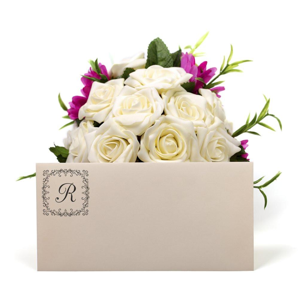 Custom floral monogram R rubber stamp on a wedding envelope with white roses and purple flowers.