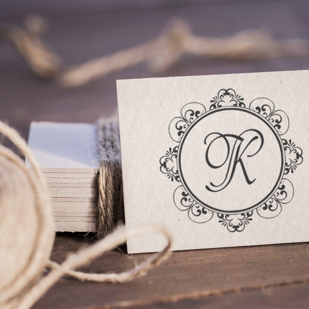 Custom monogram rubber stamp with ornate letter K on cardstock, perfect for personalized wedding stationery and branding.