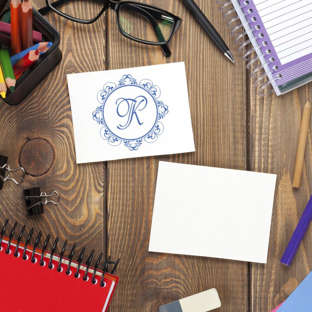 Custom monogram rubber stamp design on a desk with stationery and blank card for personalized branding and stationery use.