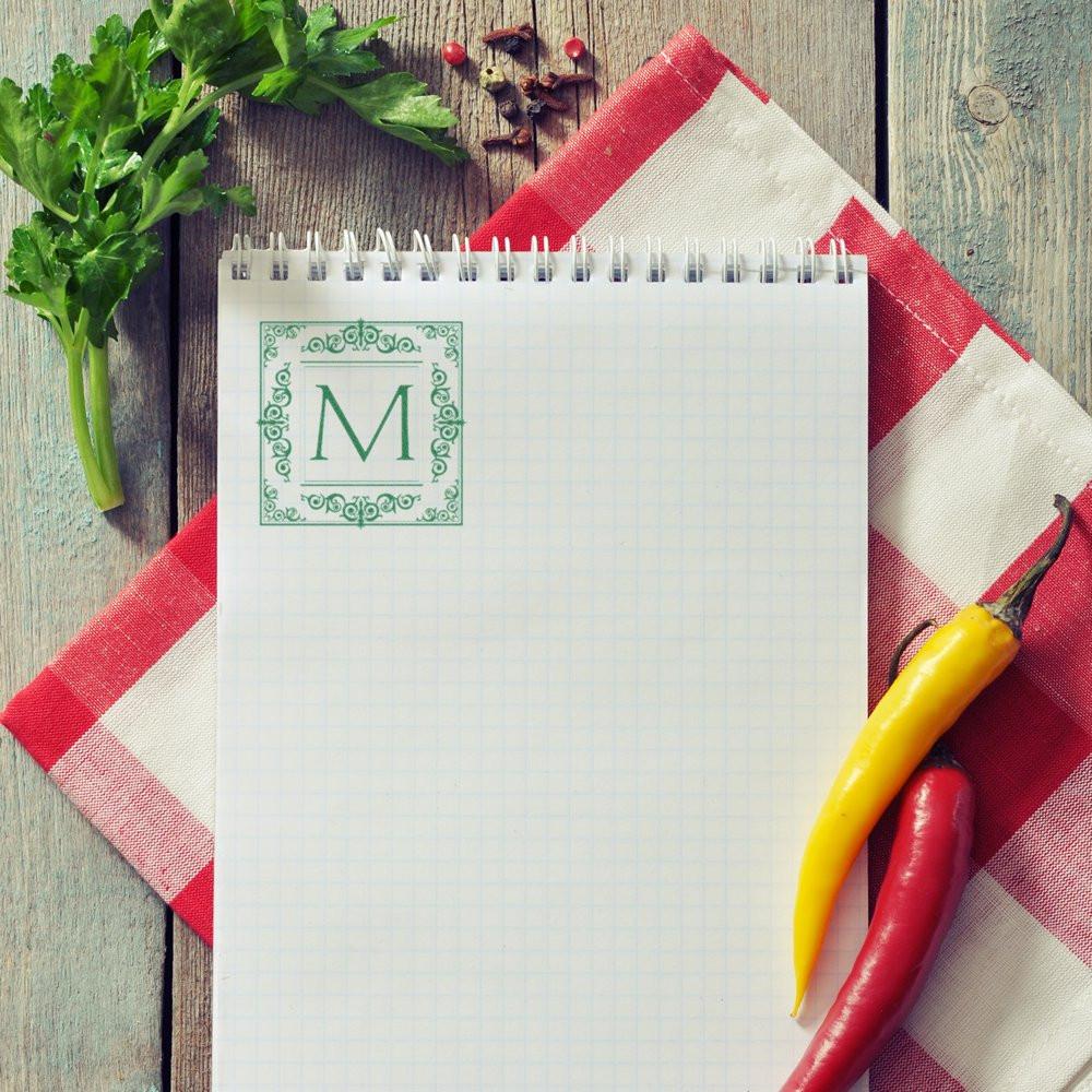 Personalized monogram rubber stamp on recipe notebook for custom kitchen branding and gourmet stationery.