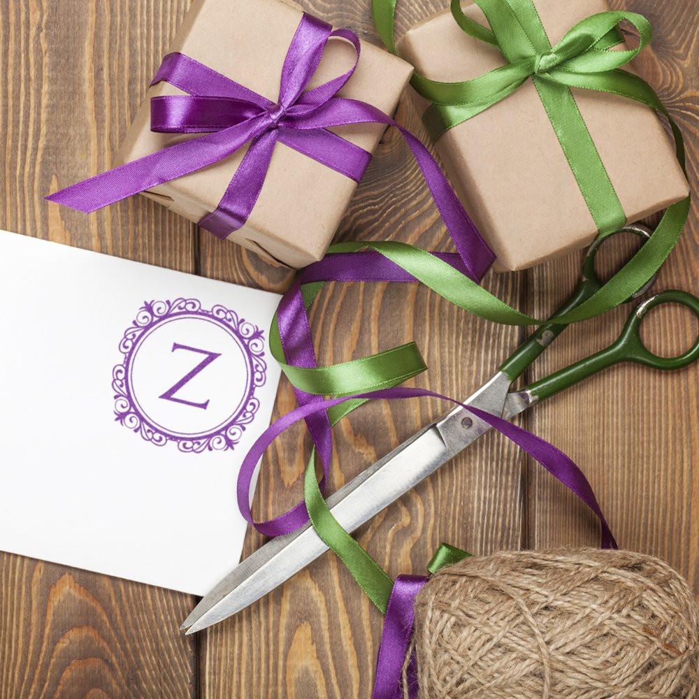 Personalized rubber stamp monogram on gift wrap with ribbons and wrapped presents for custom packaging and crafts