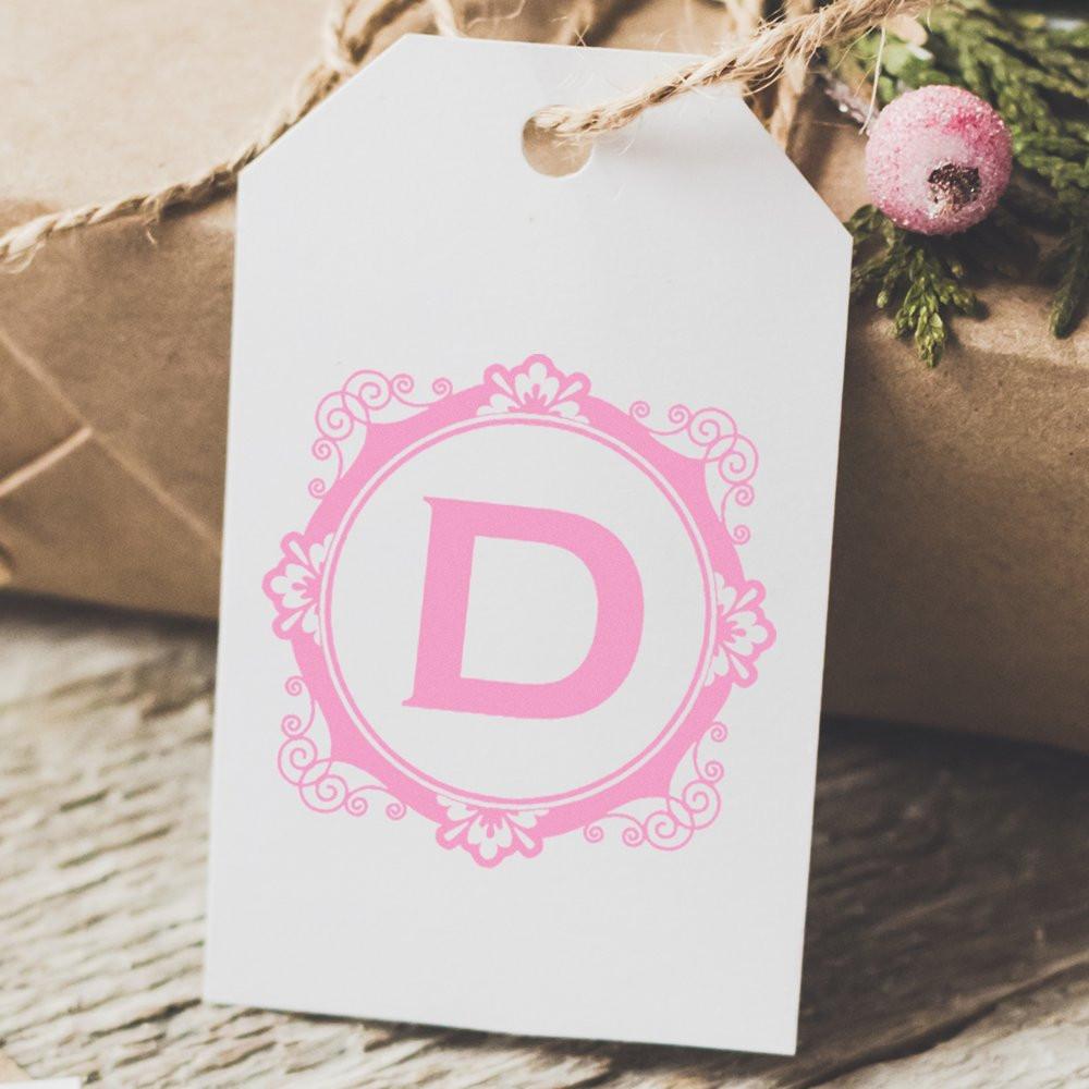 Pink monogram D rubber stamp on a white gift tag for personalized gifts and packaging.
