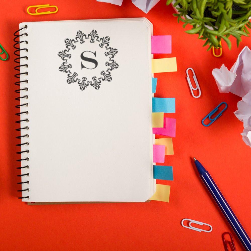Custom monogram rubber stamp on notebook with sticky tabs and office supplies, ideal for personalized stationery branding.