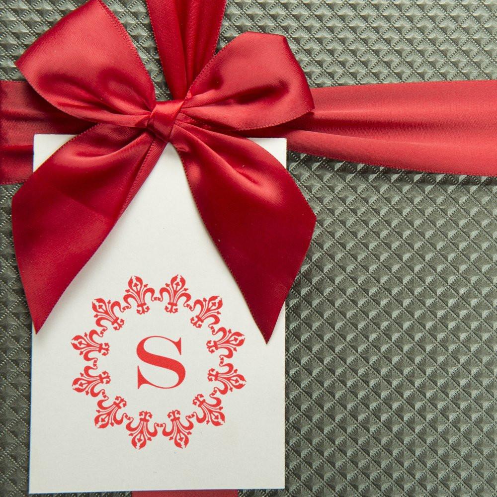 Personalized monogram rubber stamp design on a gift tag with red ribbon bow for wedding favors and packaging