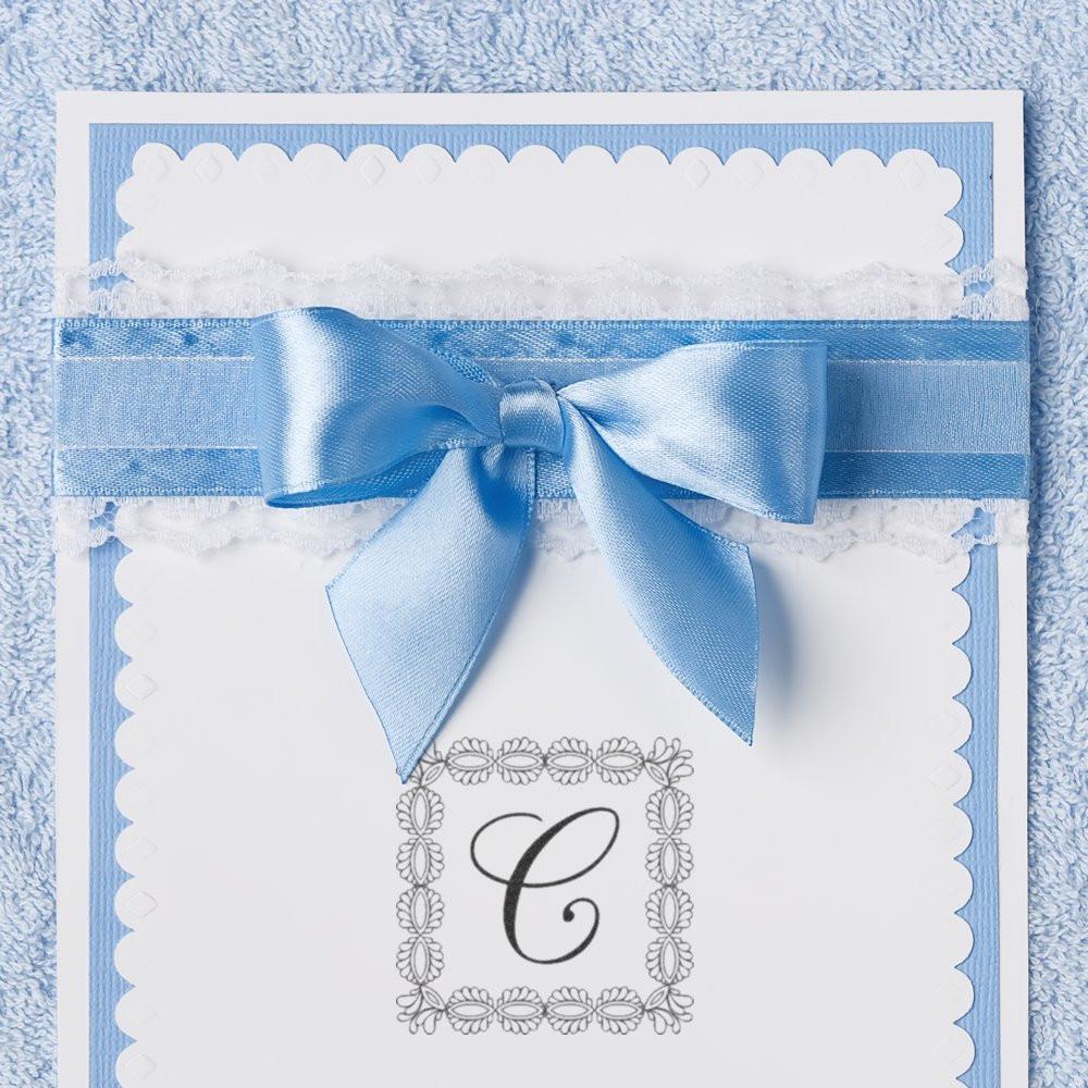 Handmade blue card with a monogram rubber stamp, decorative bow, and lace trim for elegant custom stationery.