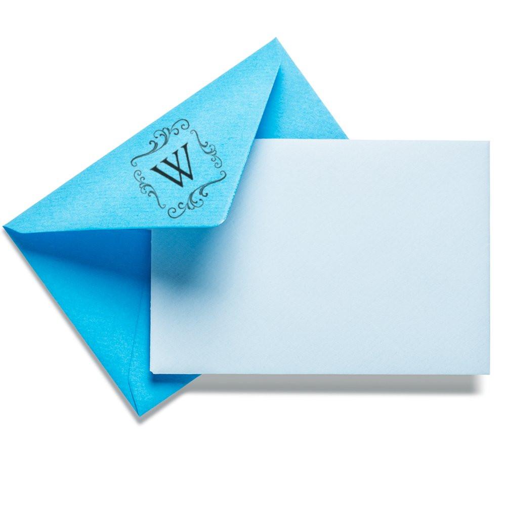 Custom monogram rubber stamp on blue envelope and blank card for personalized stationery and invitations.