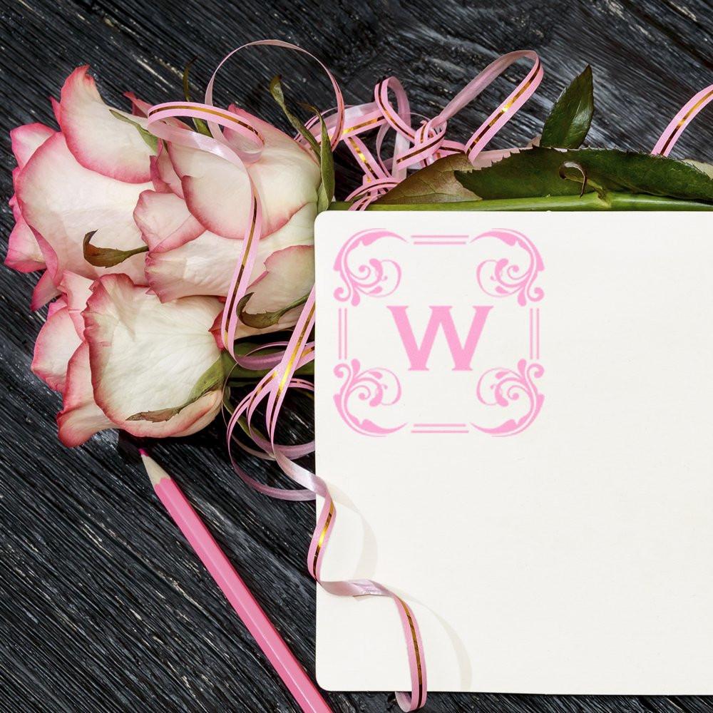 Pink monogram W rubber stamp on floral note card with roses and ribbon, ideal for custom wedding stationery and branding.