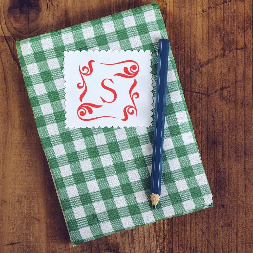 Green gingham monogram notebook with red letter S emblem and pencil on rustic wooden table, personalized stationery for writing notes