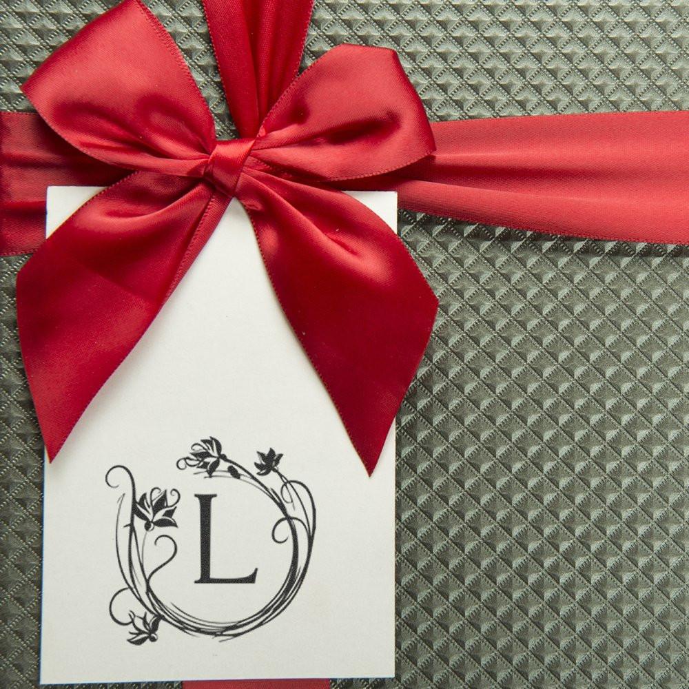 Custom floral monogram rubber stamp with letter L on a gift tag, ideal for wedding favors and personalized packaging.