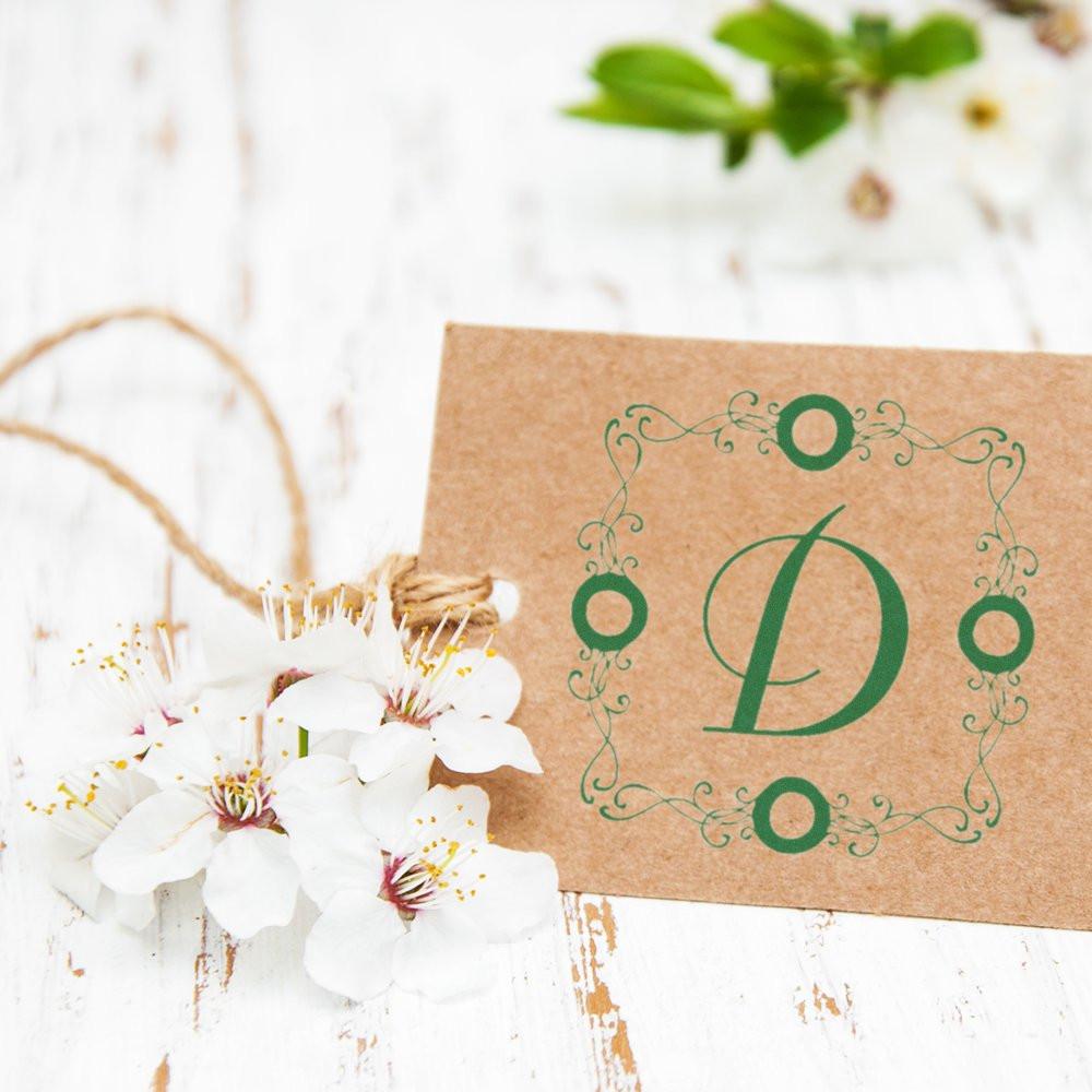 Personalized monogram rubber stamp with ornate floral frame on kraft card, styled for wedding invitations and stationery.