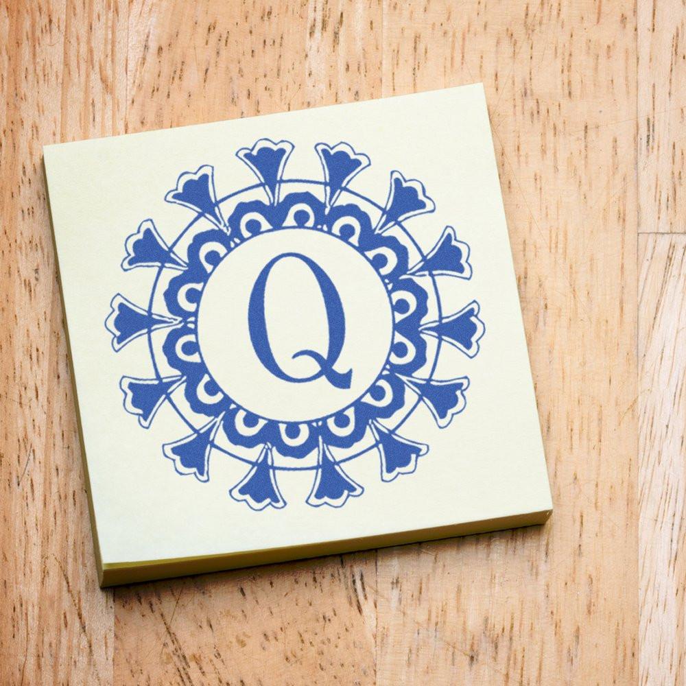 Decorative blue monogram Q emblem on cream stationery/gift card, with floral ornament for branding initials and invitations.