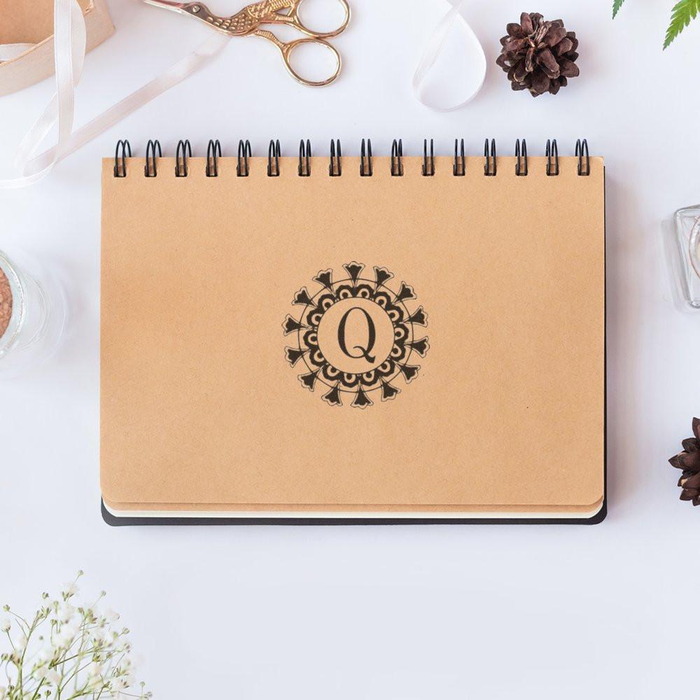 Monogrammed kraft spiral notebook with letter Q on desk with stationery scissors, ideal for study notes or personalized gifts