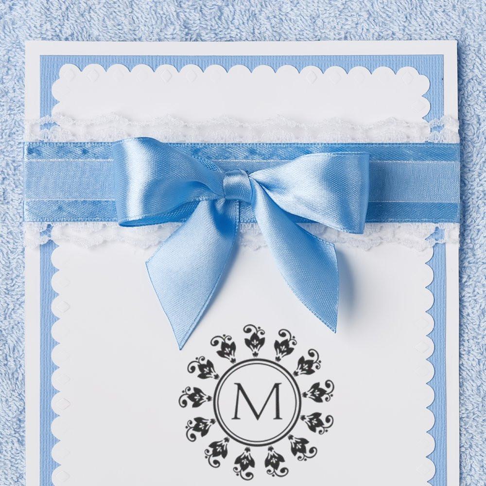 Custom monogram rubber stamp on elegant wedding invitation with blue ribbon and bow, ideal for personalized stationery.