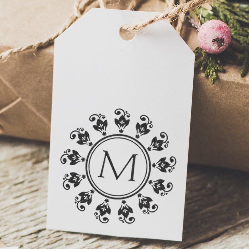 Custom monogram rubber stamp design with floral border on a gift tag for personalized packaging or wedding favors