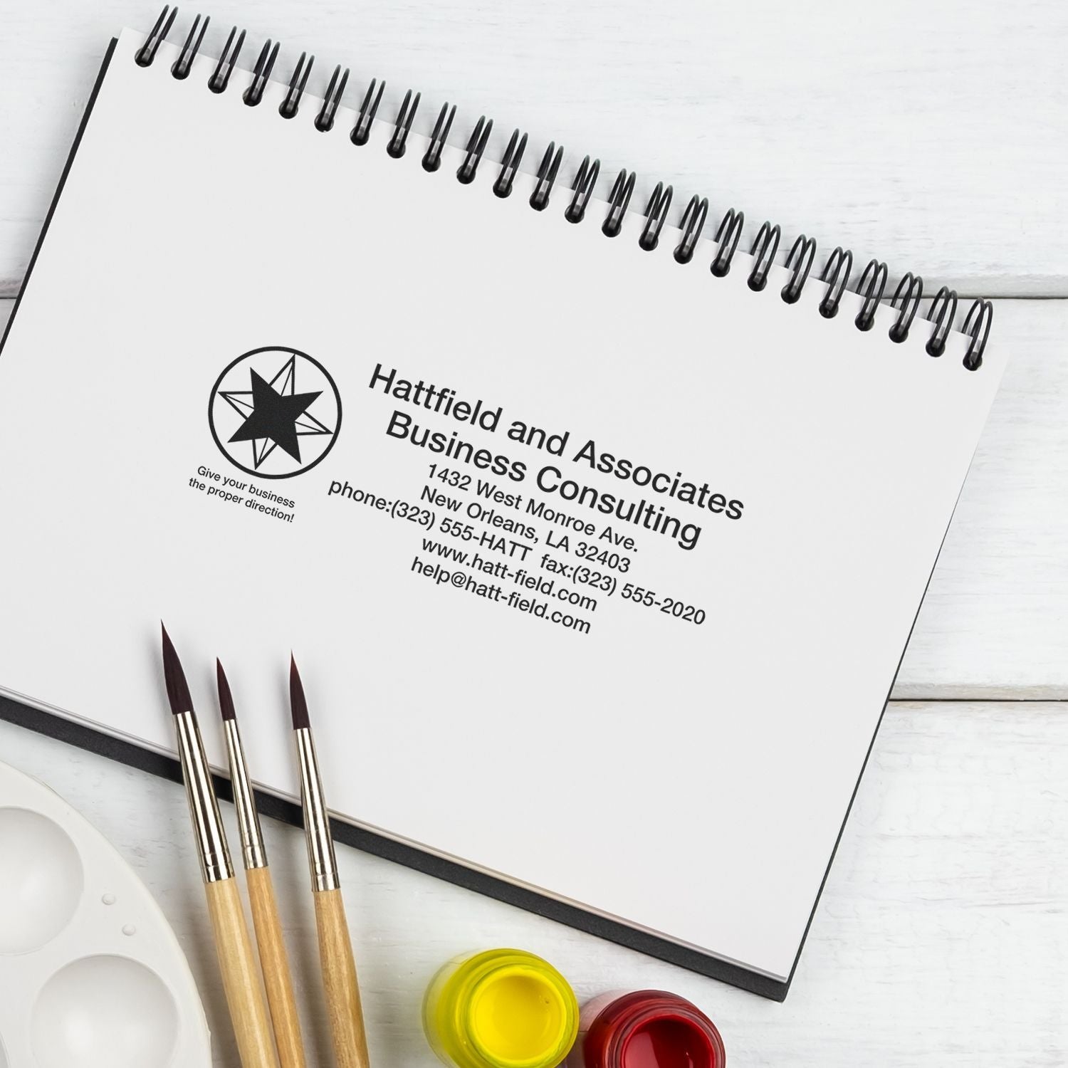 Hattfield and Associates Business Consulting contact page on notebook with phone and email details for business consulting services.