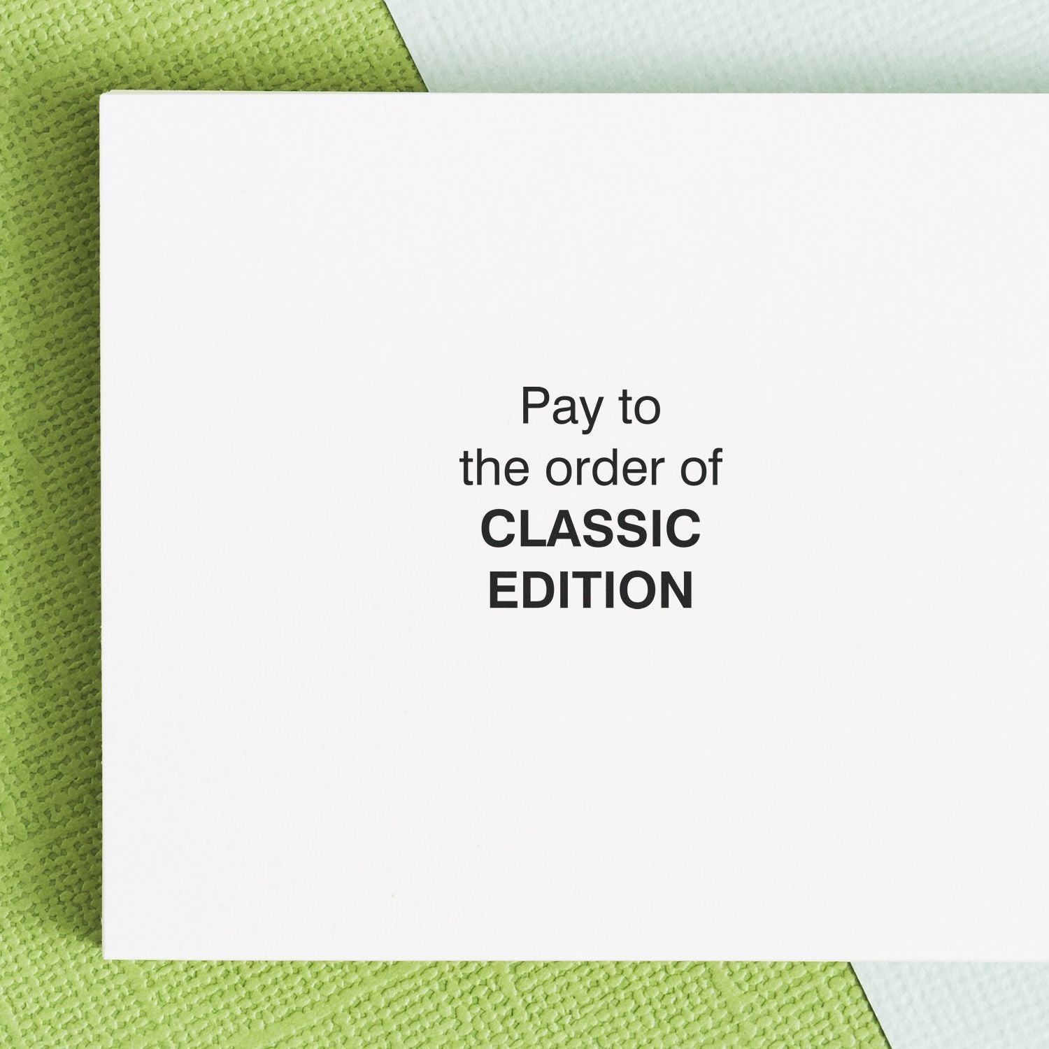 Payment check wording Pay to the order of CLASSIC EDITION shown on a white card over a green textured background