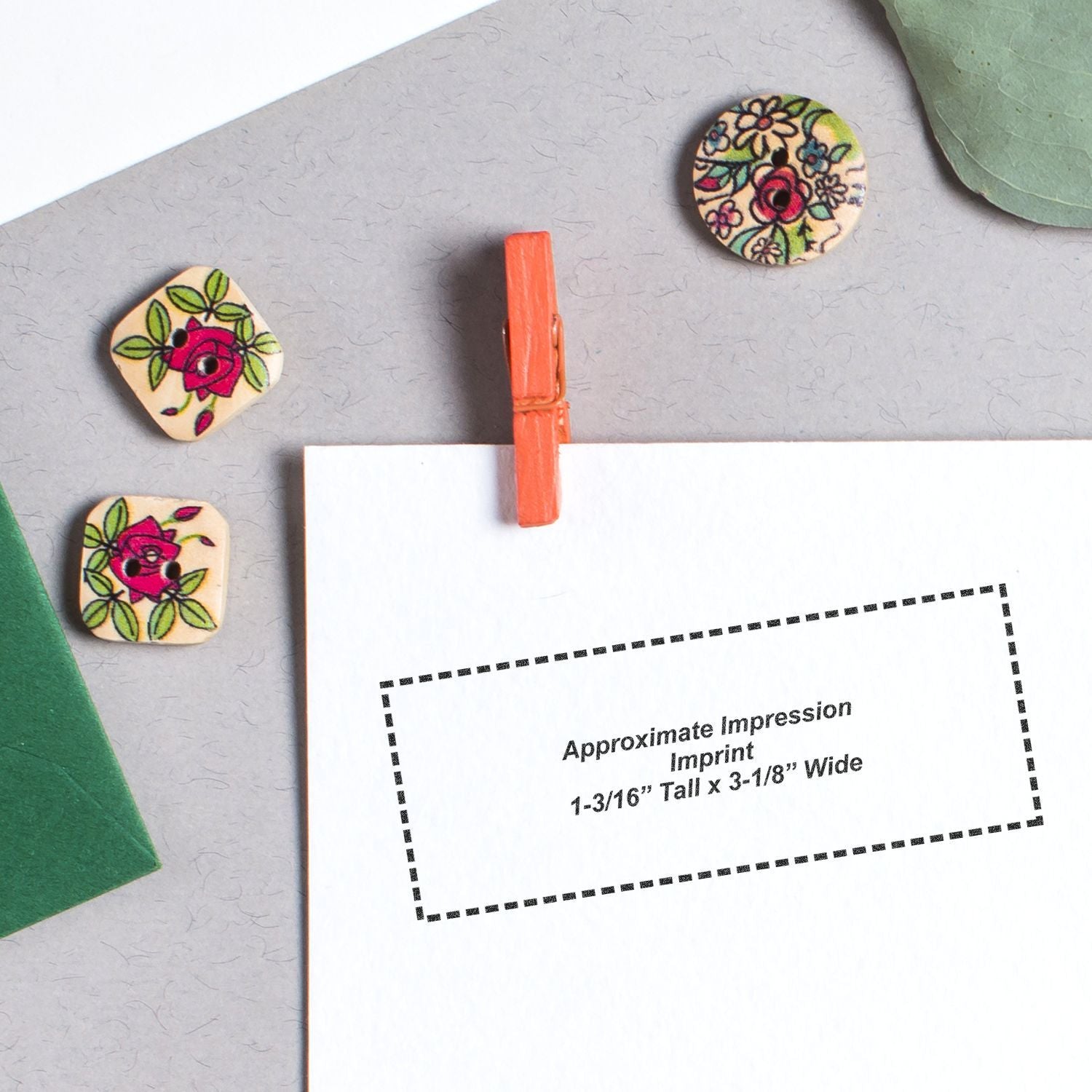 Photo of floral wooden buttons and imprint size guide showing approximate impression dimensions: 1-3/16" tall x 3-1/8" wide.