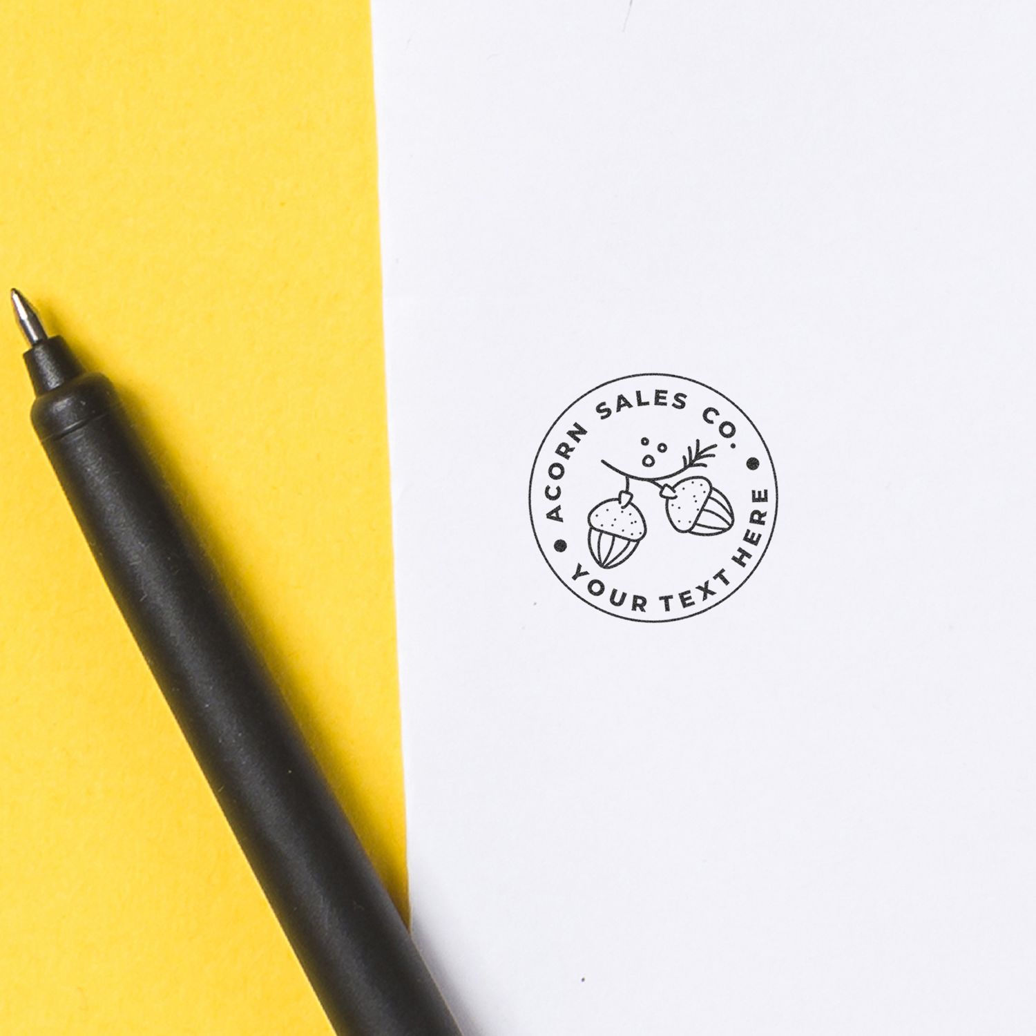 Yellow notepad and black pen with Acorn Sales Co logo stamp for sales branding and contact info.