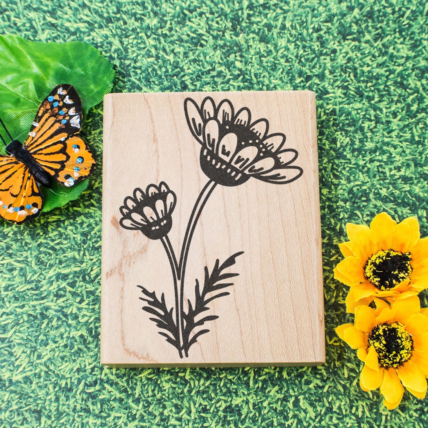 Wooden floral stamp with butterfly and yellow sunflowers on green grass background
