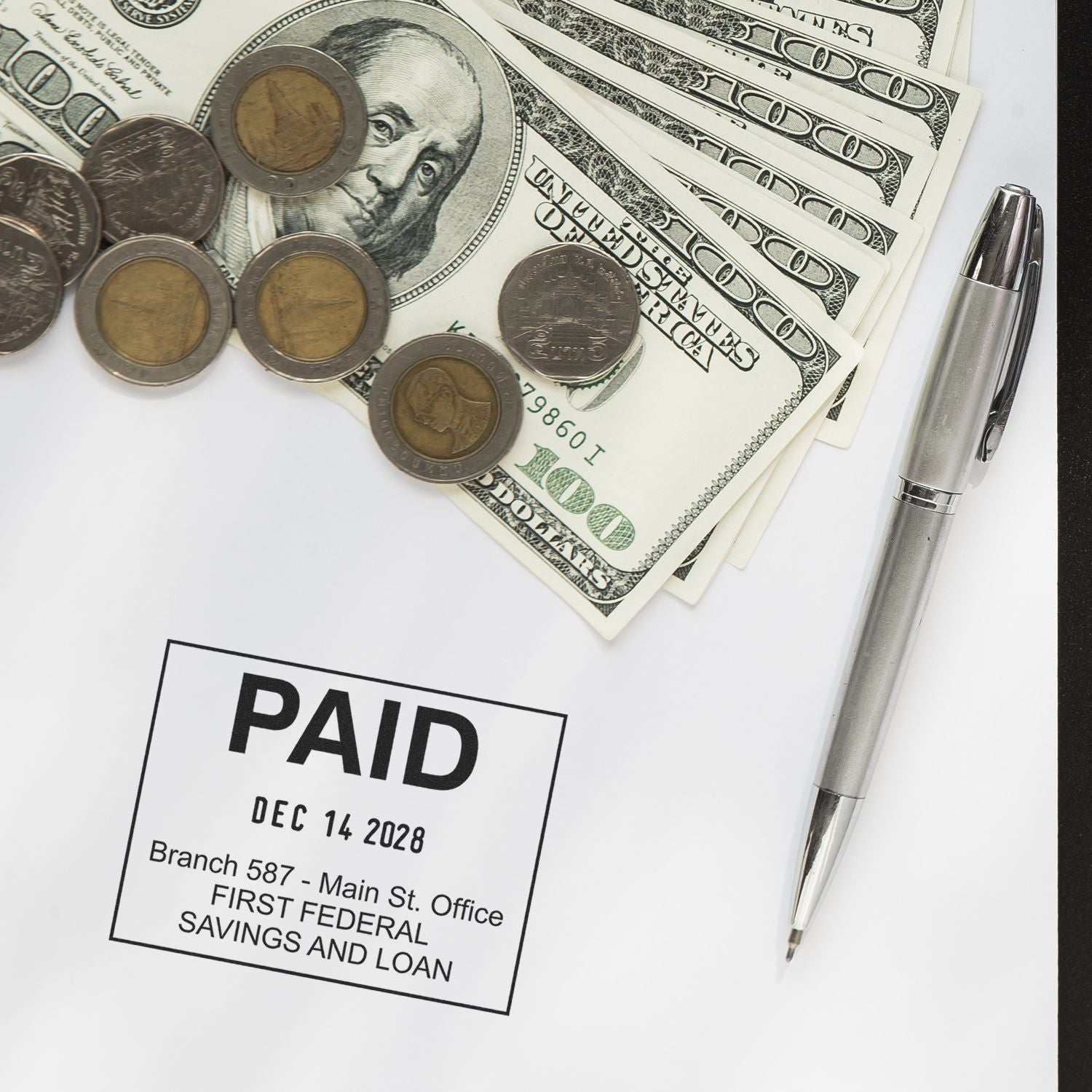 Paid bill stamp with US dollar bills, coins, and pen on a financial document