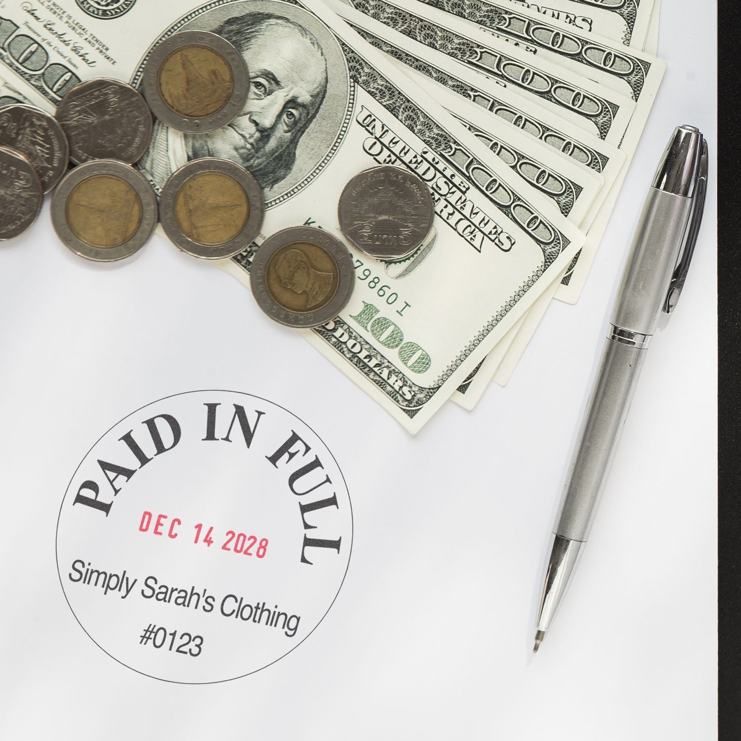 Paid in full stamp on invoice with U.S. dollar bills, coins, and pen, representing complete business payment.