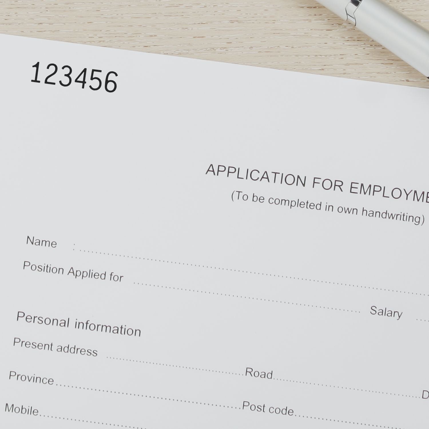 Blank employment application form on desk with pen and sample number, job application document for hiring and personal information.