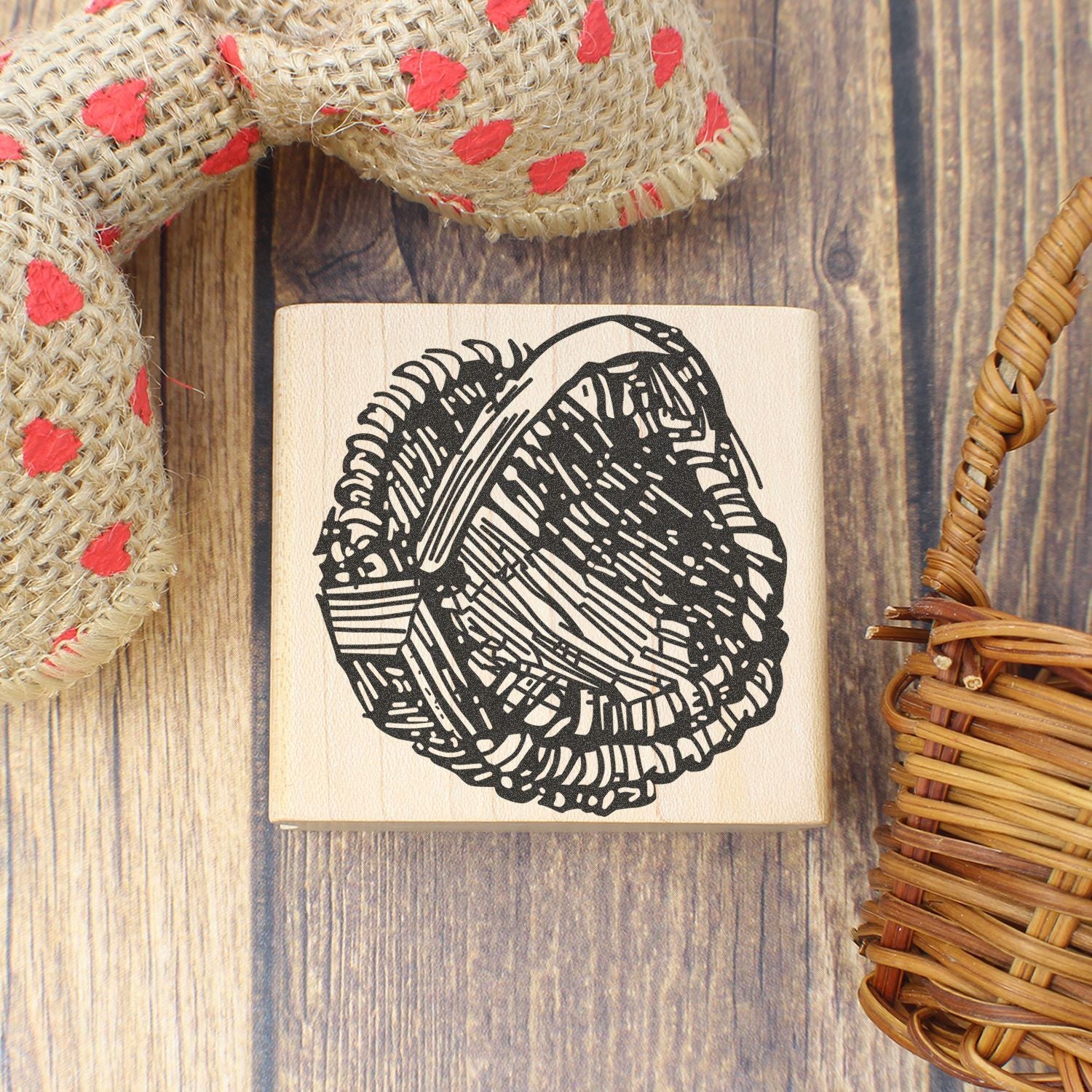 Handmade wooden rubber stamp with a bird nest design on a rustic wood background with burlap and wicker accents.