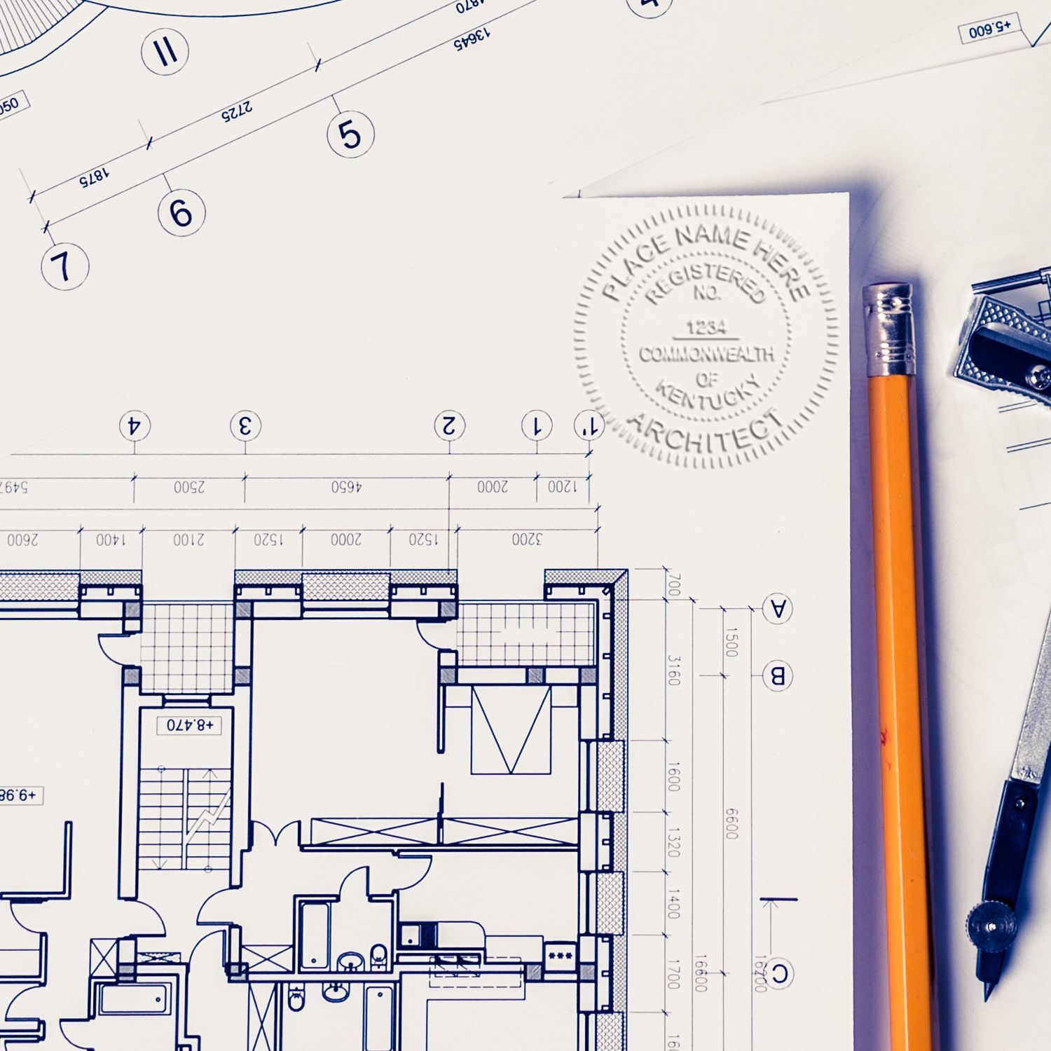 Architectural blueprint floor plan with pencil, compass, and architect stamp on drafting paper.