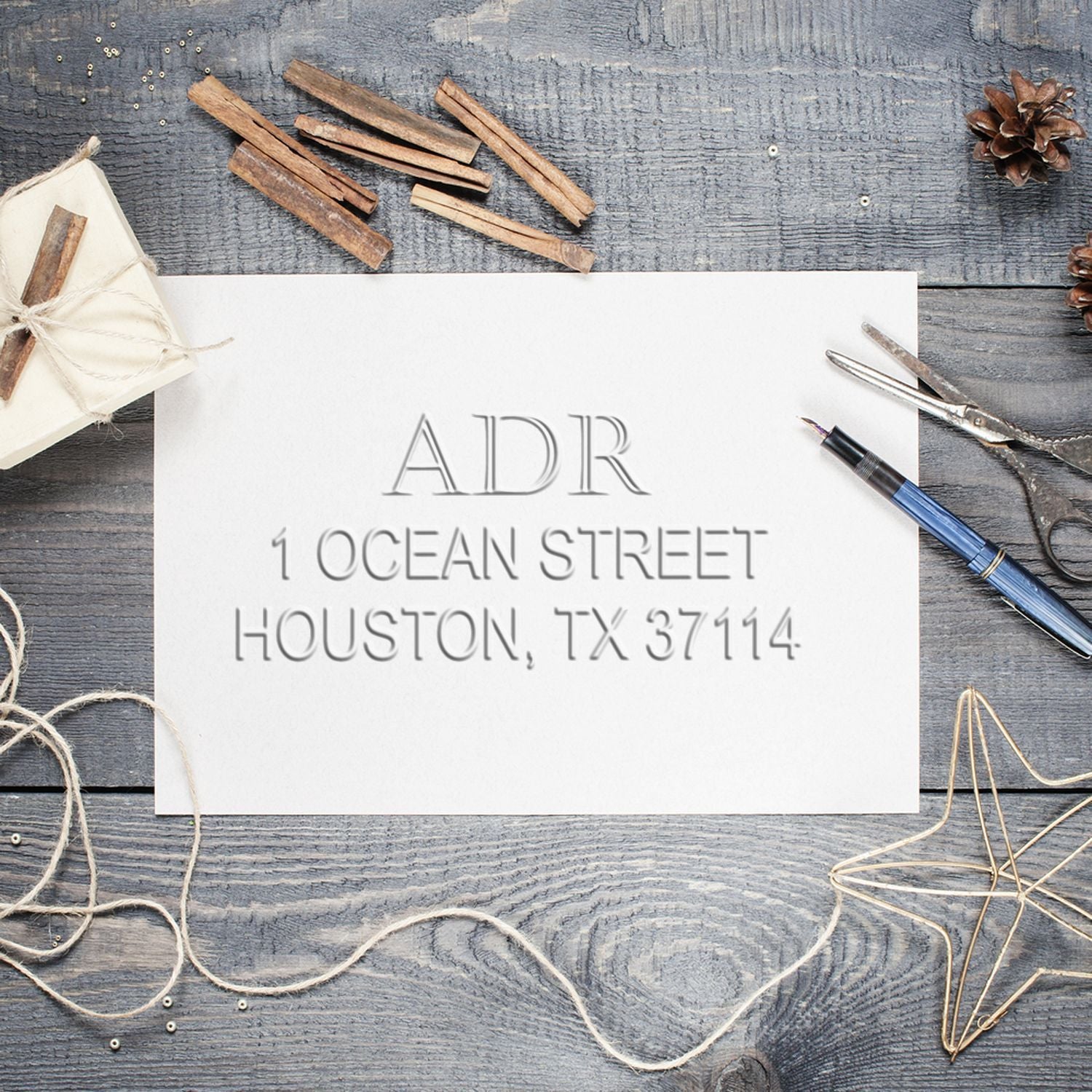 Custom address stamp with “ADR 1 Ocean Street, Houston, TX 37114” on a rustic wooden desk with stationery tools