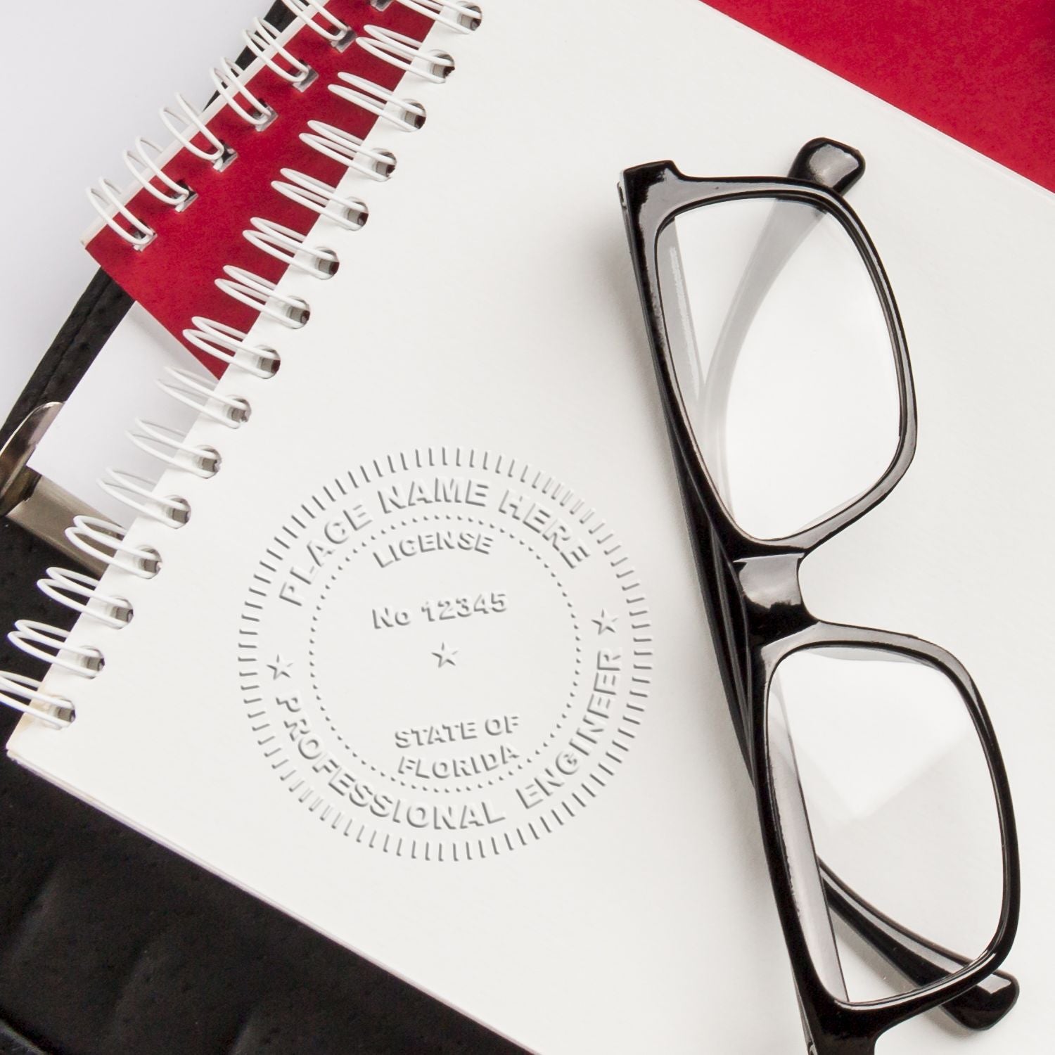 Black eyeglasses on a Florida professional engineer license document with a spiral notebook.
