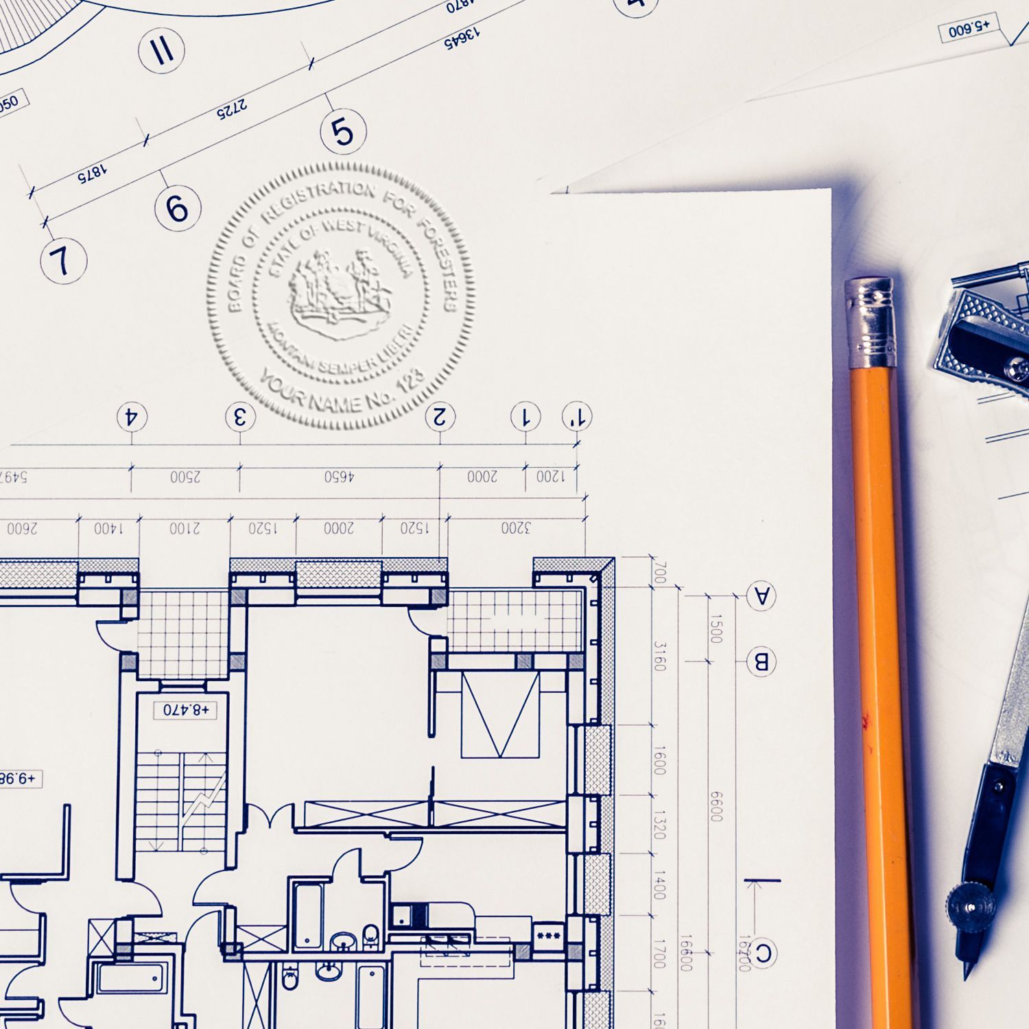 Architectural floor plan blueprint with drafting tools, pencil, and compass on a white workspace.