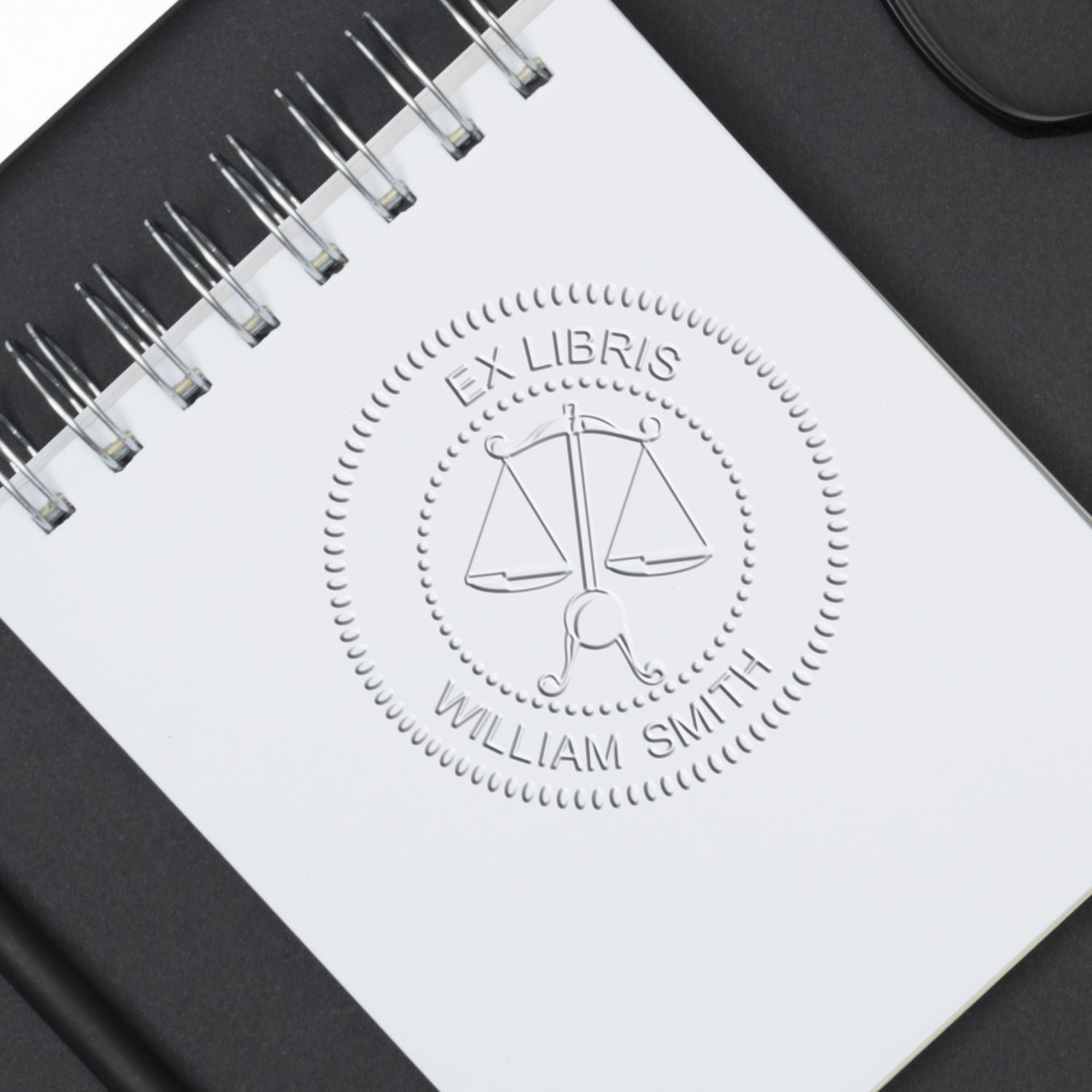 Spiral-bound notebook with embossed Ex Libris William Smith scales of justice logo on a white cover