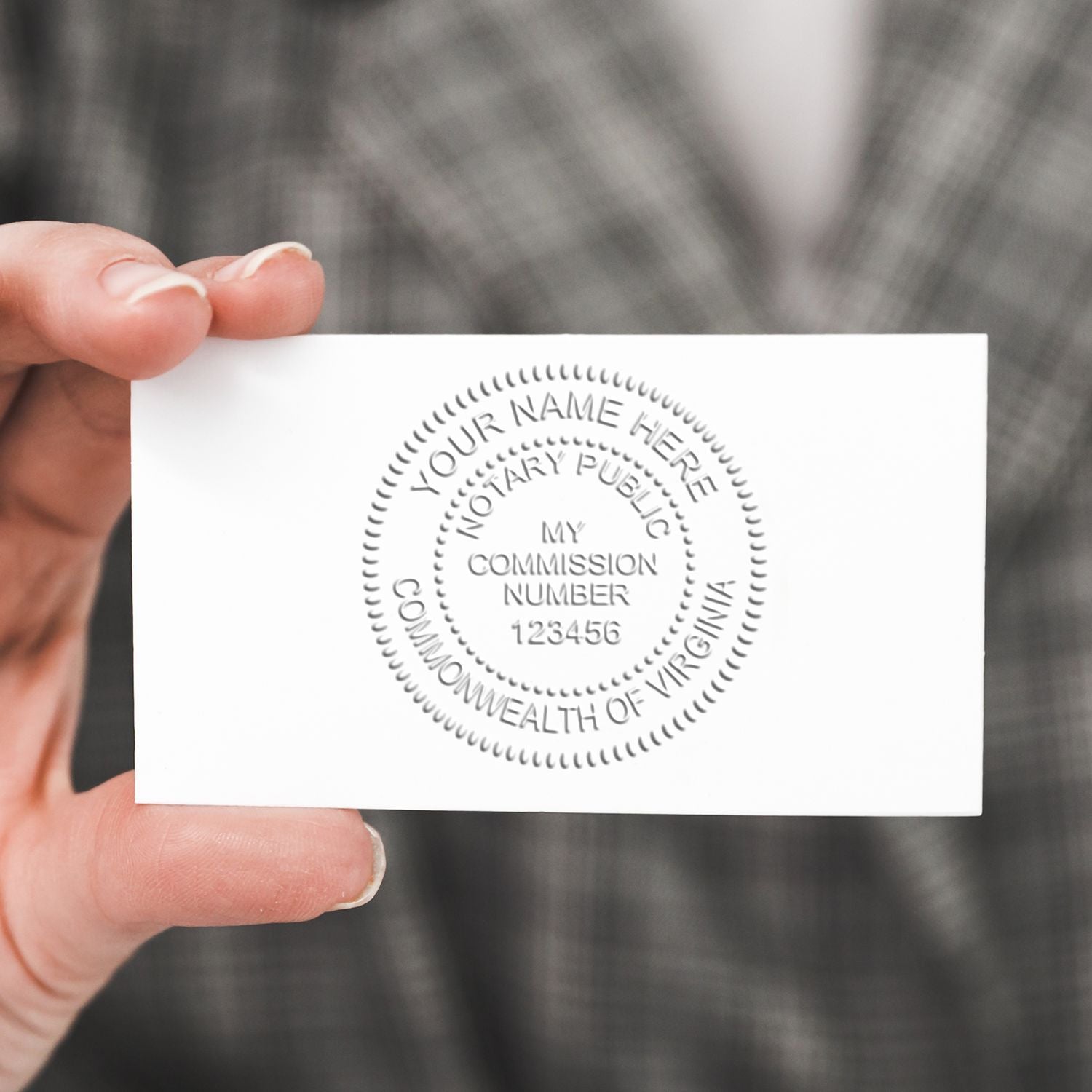 Hand holding an embossed Virginia notary public business card with seal and commission number.