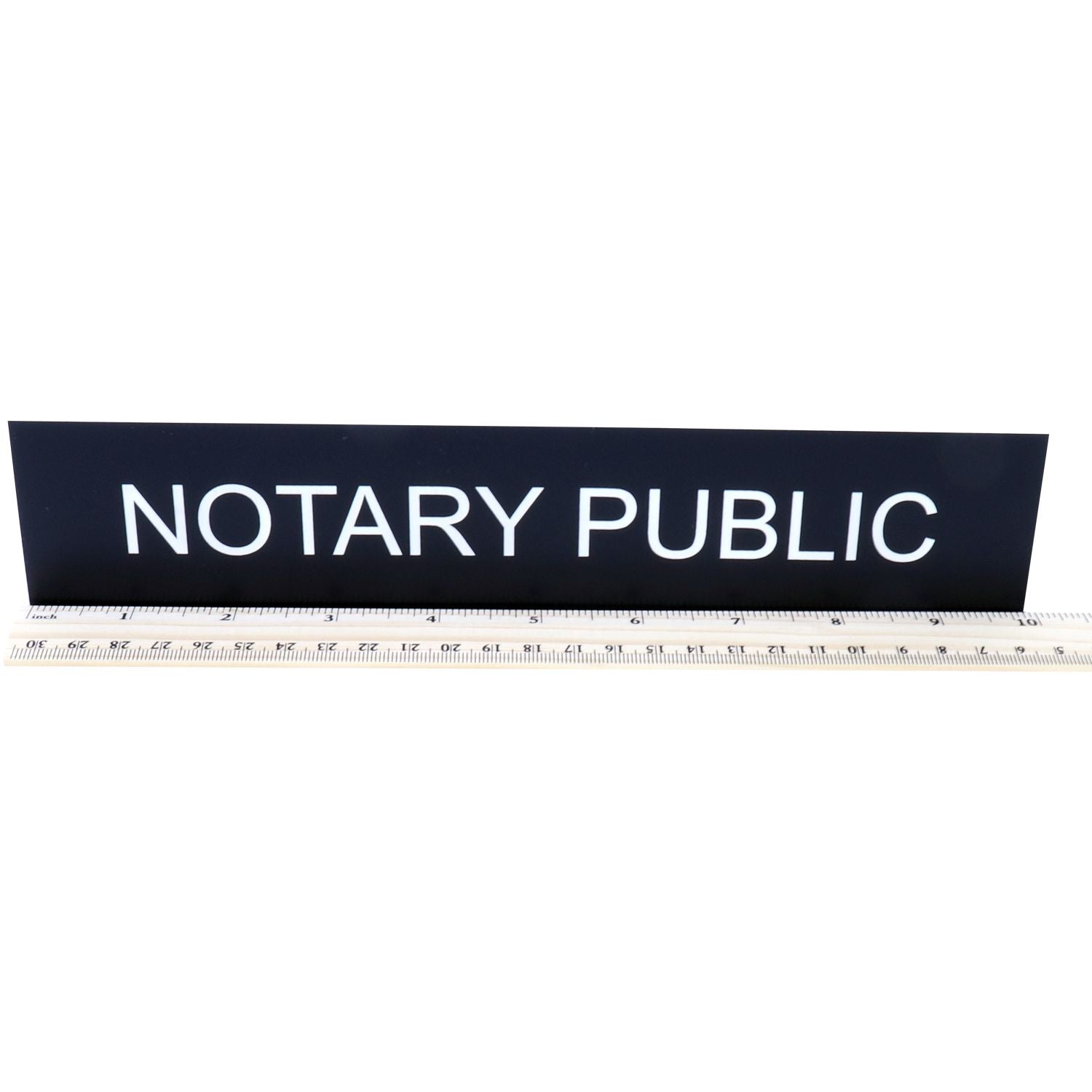 Black Notary Public sign with white lettering displayed on a ruler against a white background.