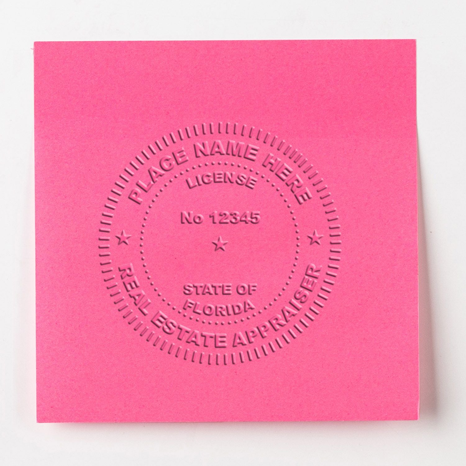 Pink embossed Florida real estate appraiser license seal with placeholder name and license number 12345 on paper.