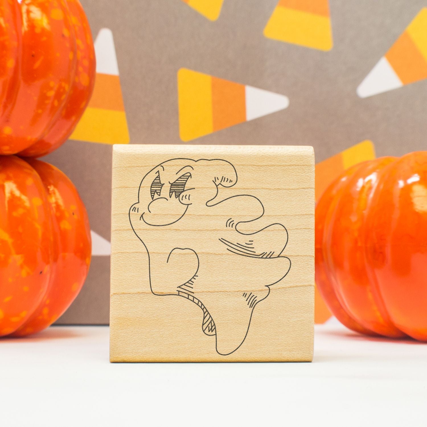 Halloween rubber stamp with a cute ghost design, surrounded by orange pumpkins and festive fall decor.