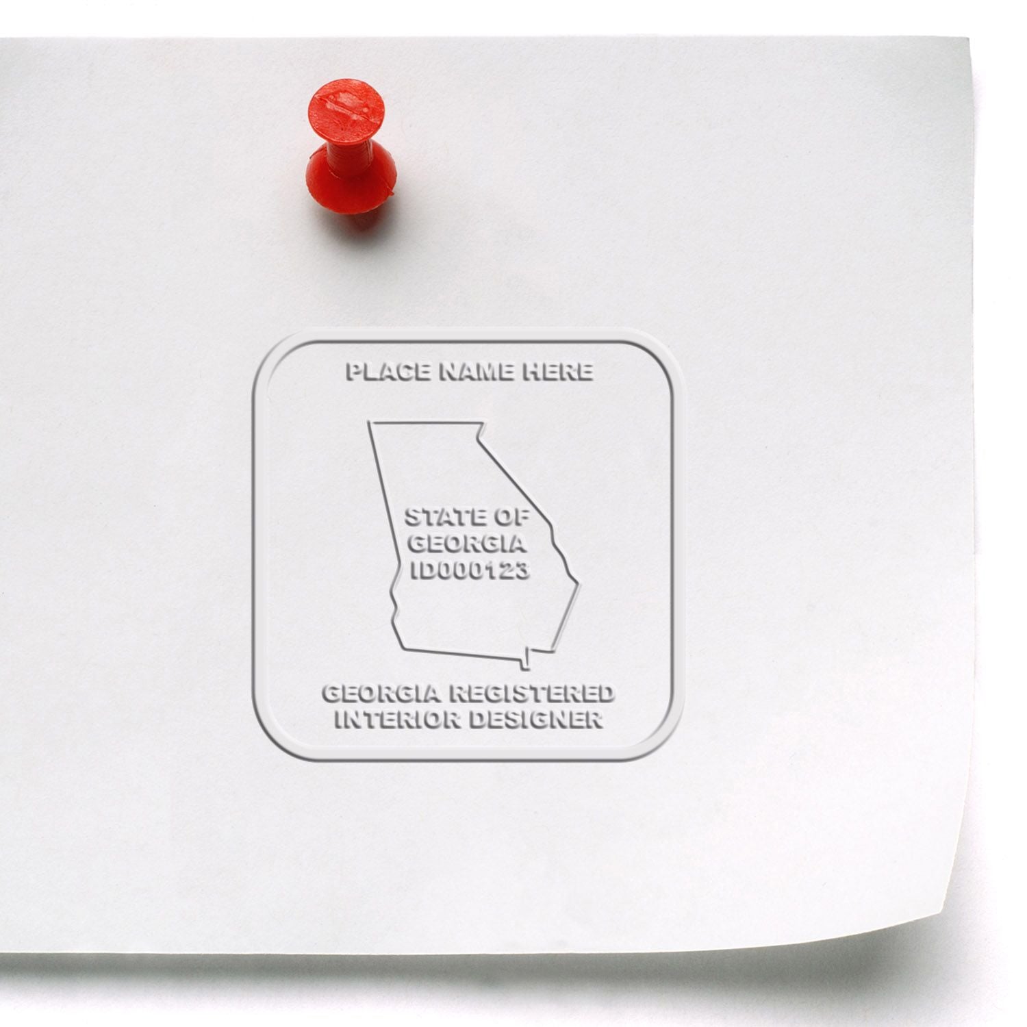 Embossed Georgia Registered Interior Designer seal on white paper pinned with a red push pin.