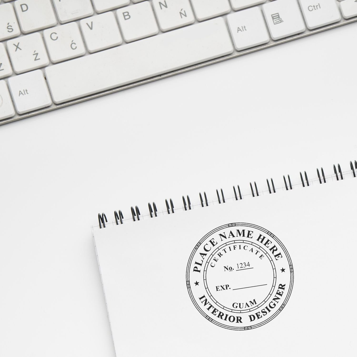 White keyboard and spiral notebook with interior designer certificate stamp on a clean desk background.