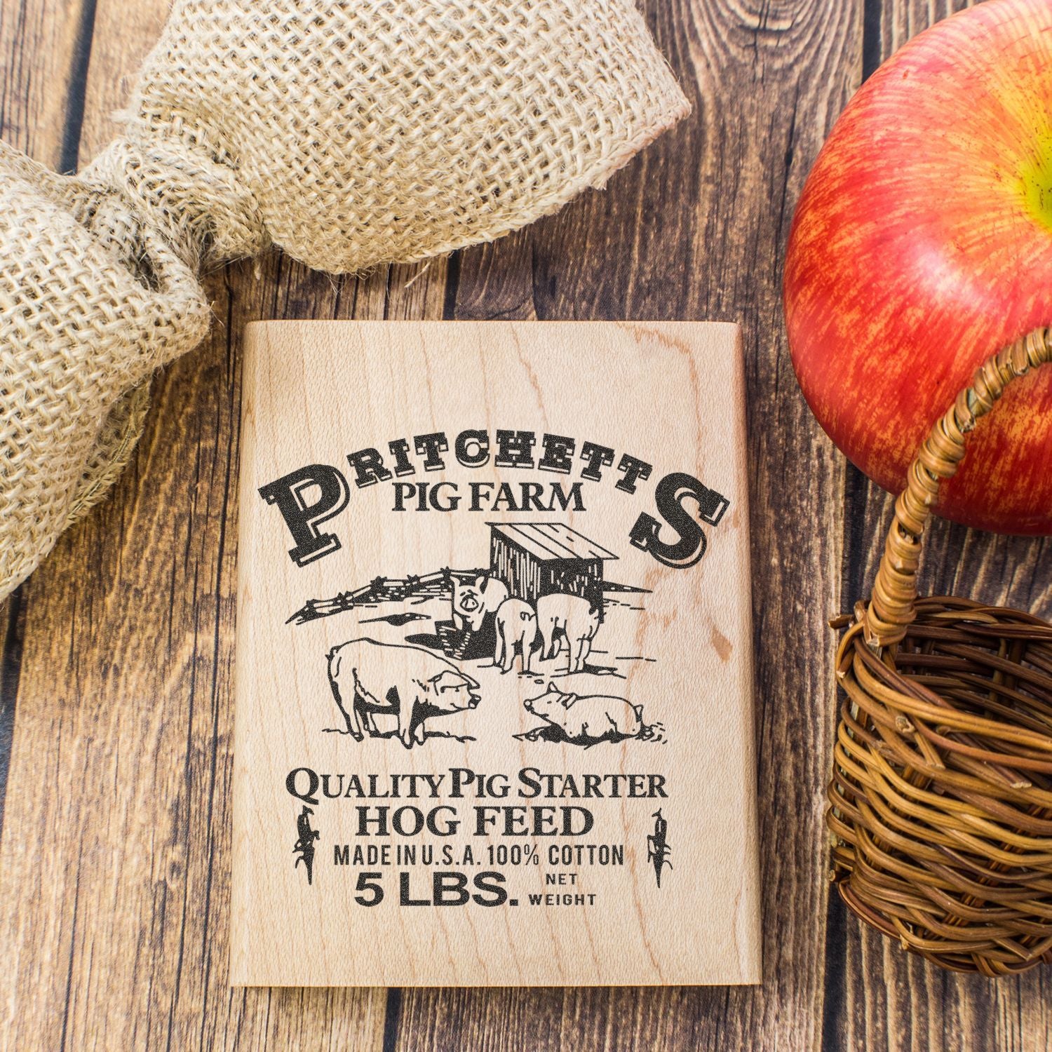 Rustic Pritchetts Pig Farm wooden sign with burlap, apple, and basket on a farmhouse wood background.
