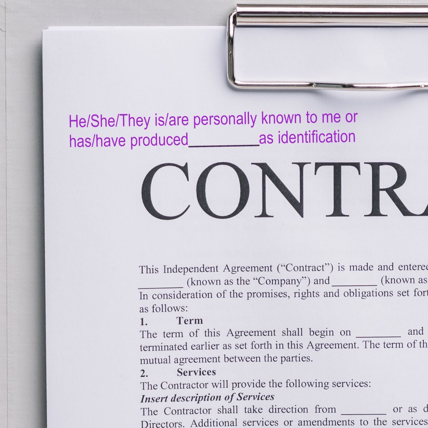 Clipboard holding an independent contractor agreement contract form with blank fields and signature section visible.